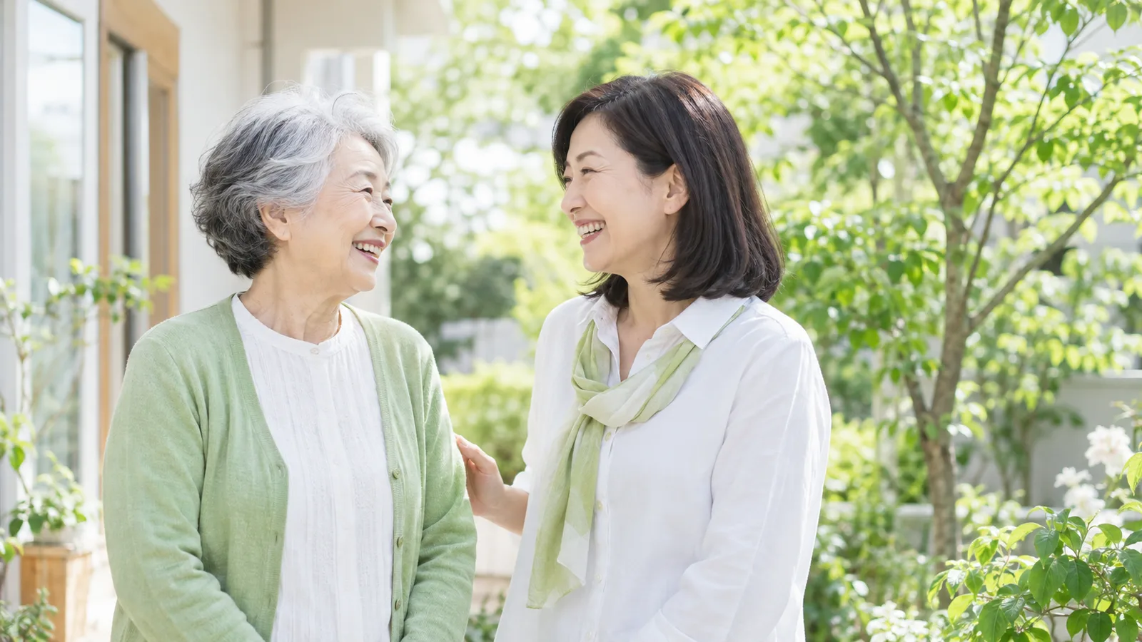 庭先で、70代の女性と娘が少し離れた所から見た横顔で笑い合っている
