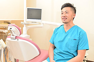 診療台のそばに座って、患者さんの方を向いて話を聞いている歯科医師
