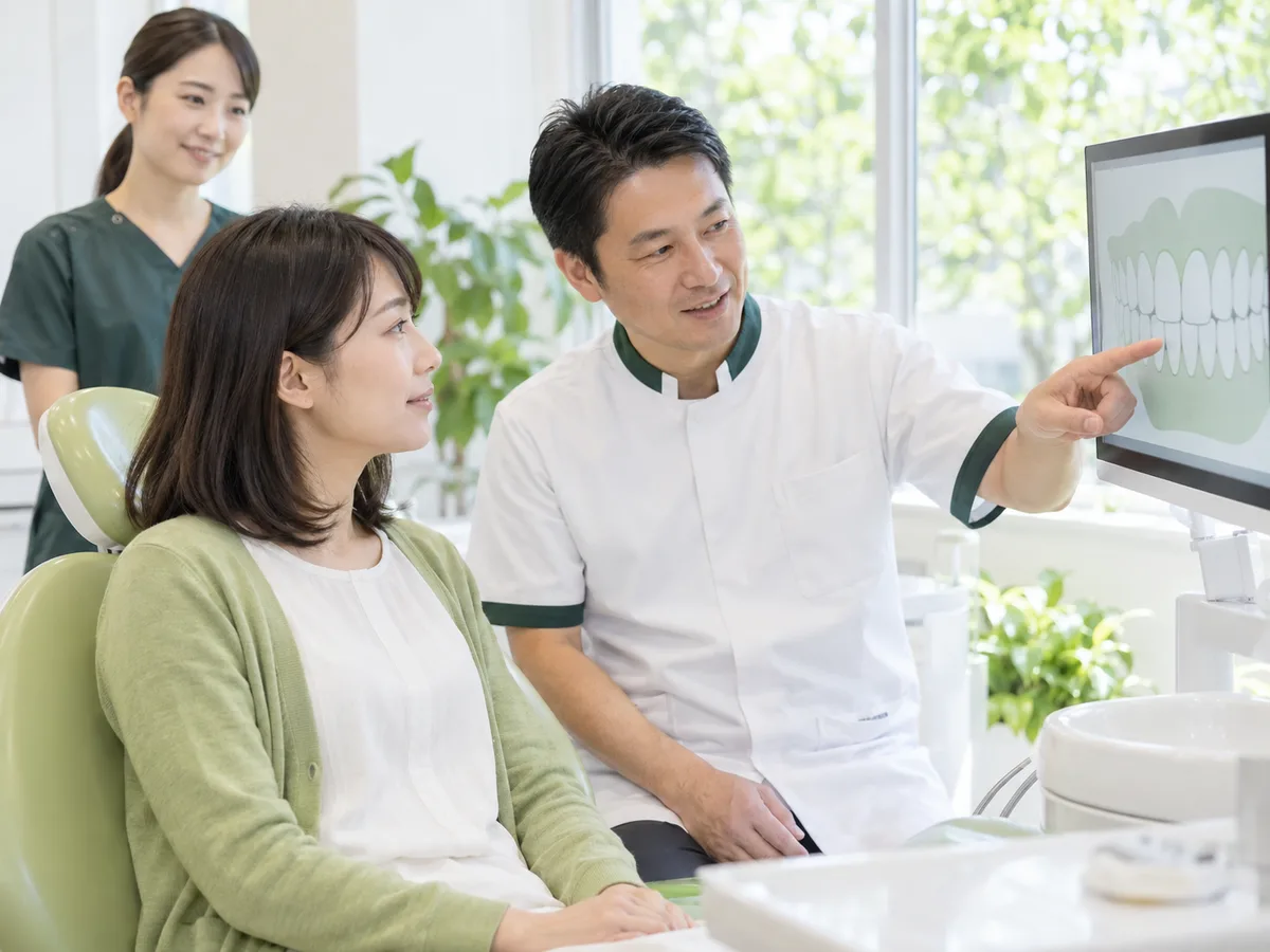 診療室で、歯科医師がモニターの図を示しながら患者さんに検査の結果を説明している