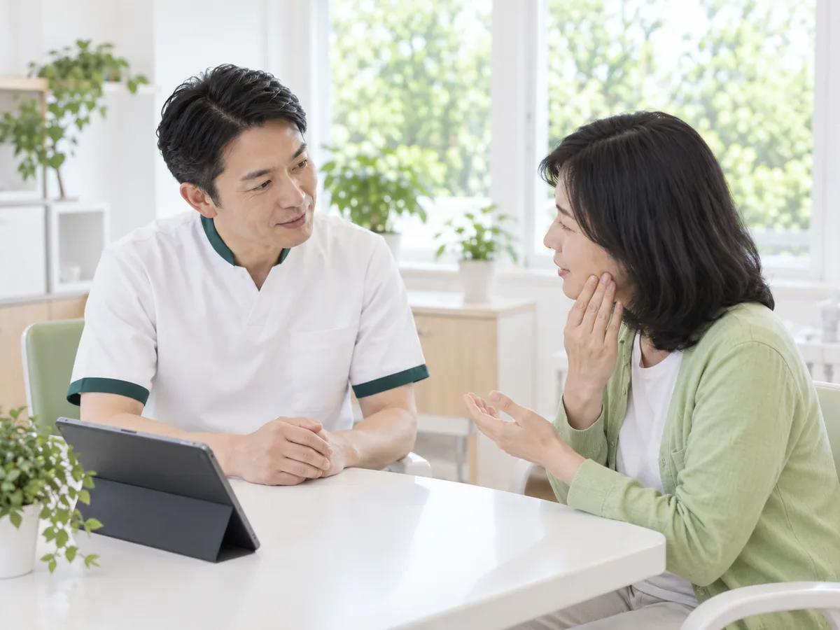相談室で、歯科医師が大学生の男性の話を身を乗り出して聞いている