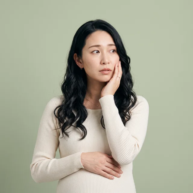 お腹に手を添え、頬に手を当てる妊婦さん